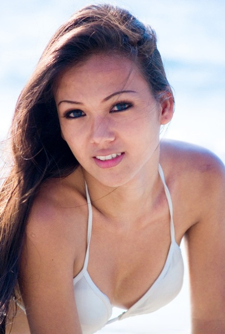 Supreme brunette doll showing her stunning body in bikini on the beach